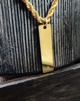 Gold necklace with a rectangular pendant on a textured surface