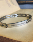 Silver bracelet with engraved names on an old book