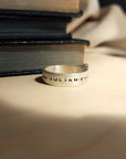 Silver ring with engraved text on a stack of books