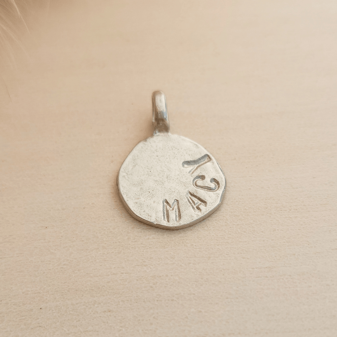 Silver pendant with 'Macy' engraved on a beige background
