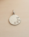 Silver pendant with 'Macy' engraved on a beige background