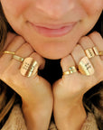 Close-up of a person wearing multiple gold rings with engraved text on their fingers.