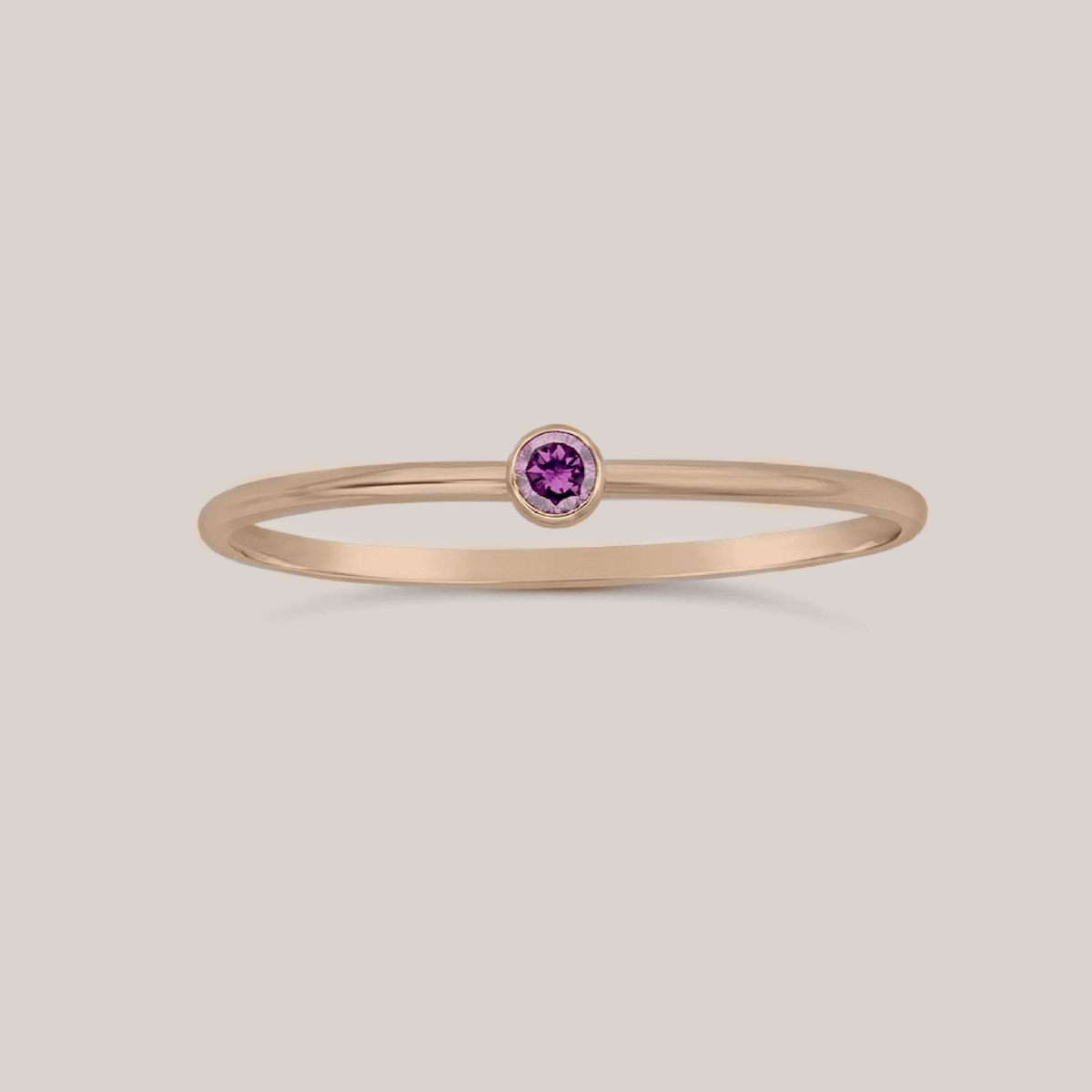 Close-up of a February birthstone ring with a 2mm amethyst crystal on a slim 1mm band, perfect for stacking or solo wear.