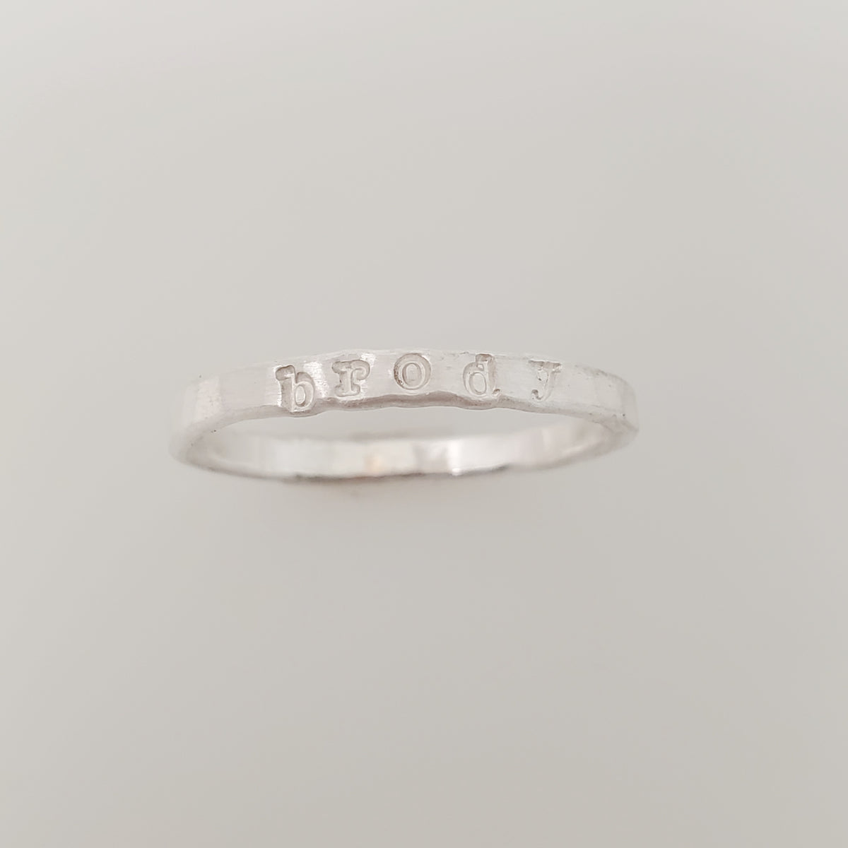 A silver stacking name ring with the name 'brody' hand-stamped on it.