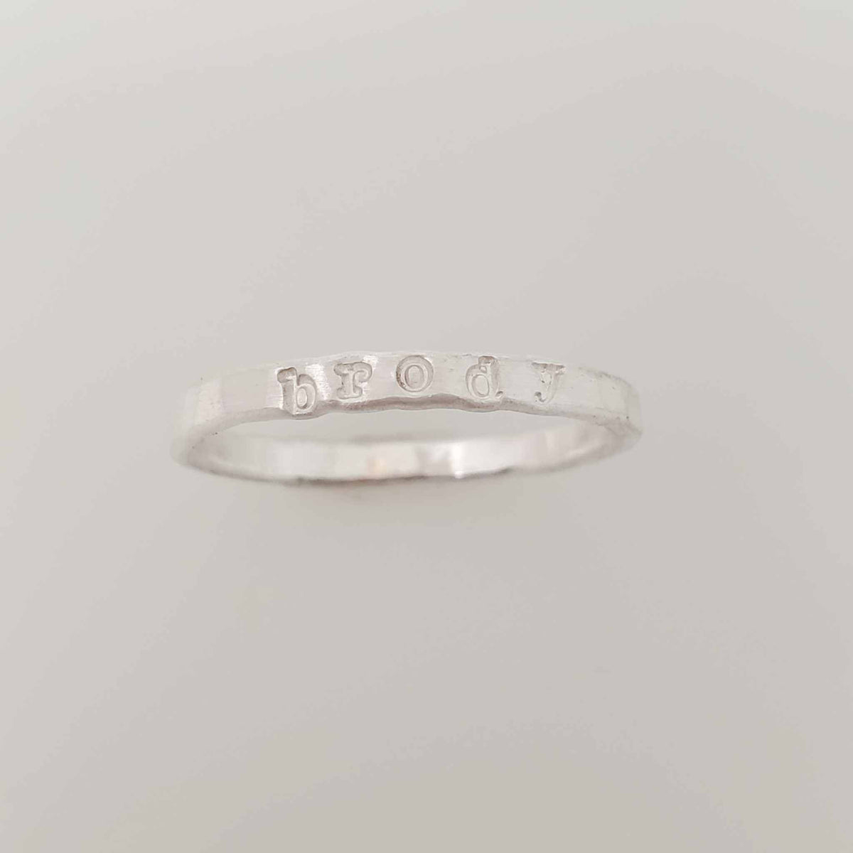 A silver stacking name ring with the name 'brody' hand-stamped on it.