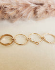 Set of gold rings on a soft beige surface with pampas grass in the background