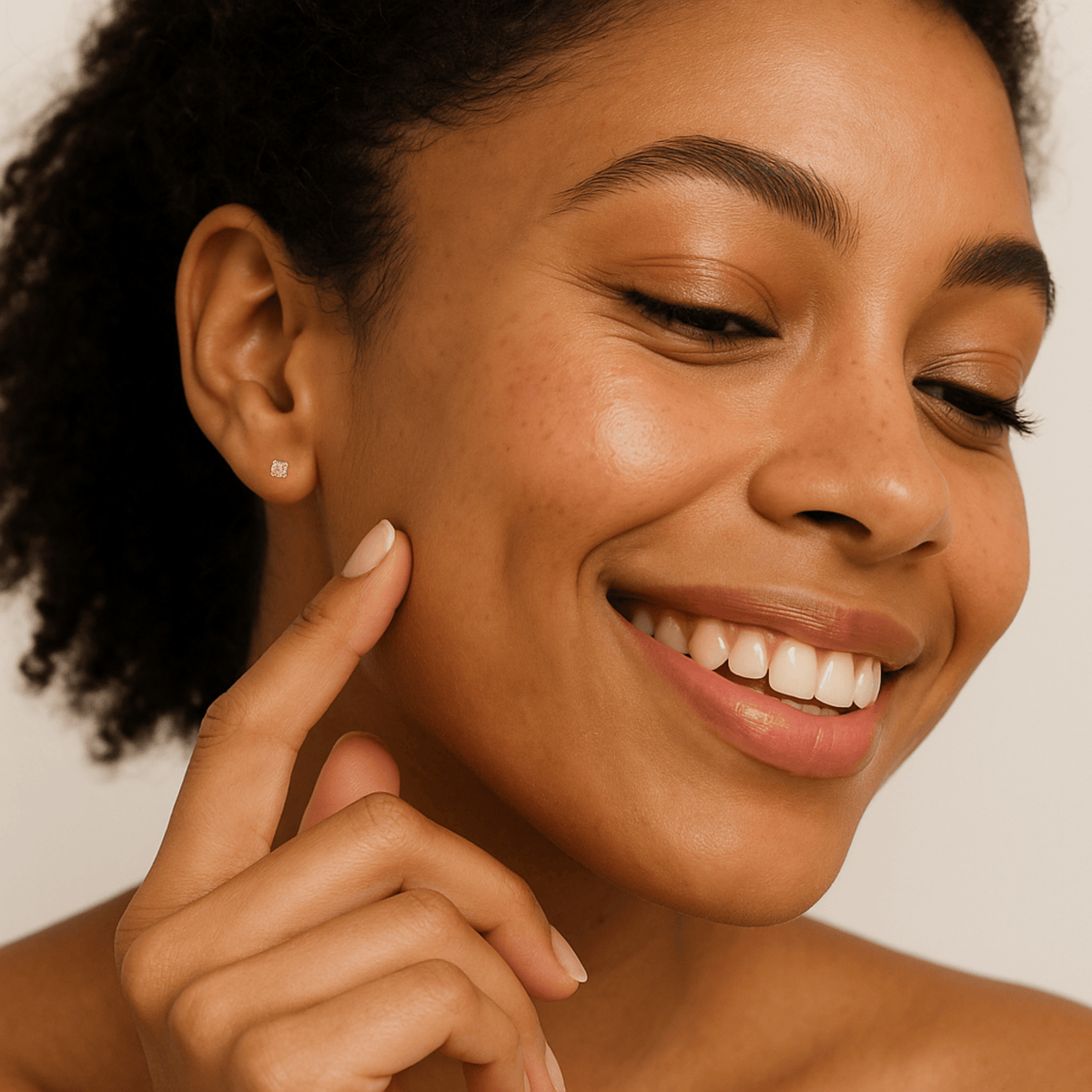 Woman smiling and touching her cheek with a neutral background