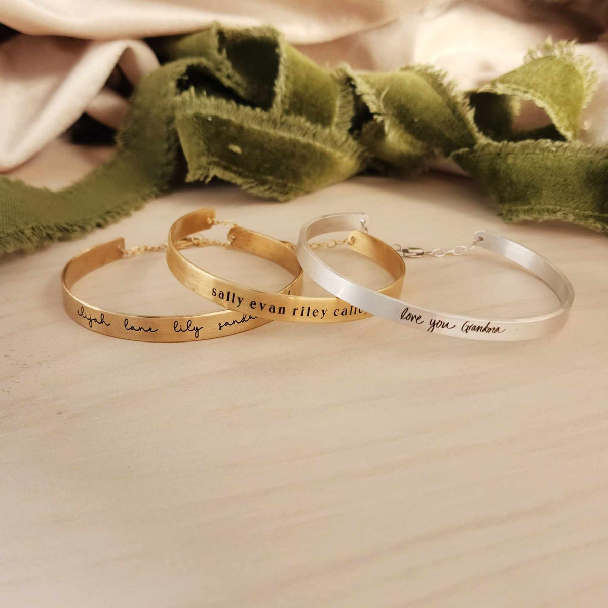 gold and silver handwriting cuff bracelet on wood table