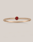A gold-filled band ring with a red garnet crystal accent, intended for stacking.