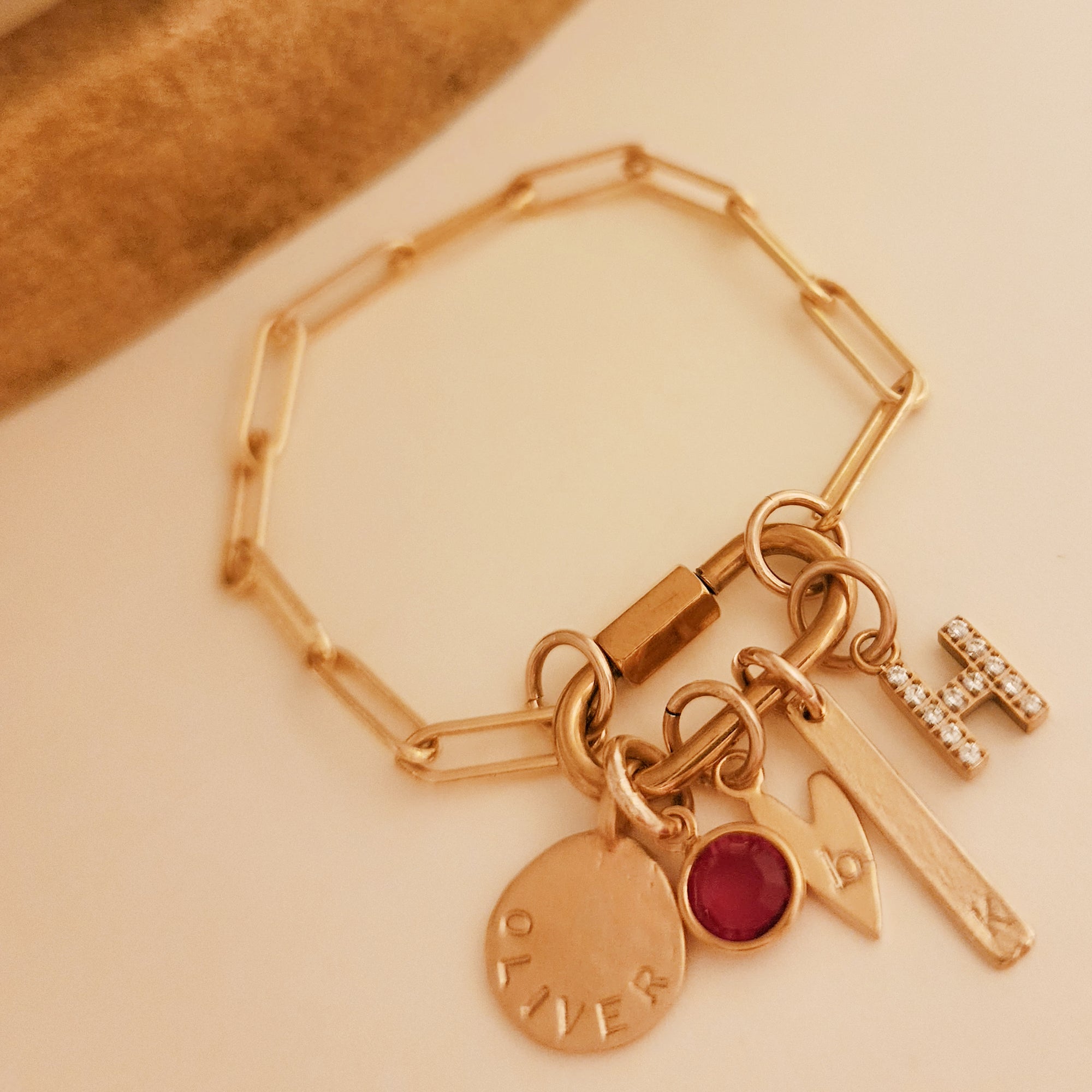Gold bracelet with various charms on a beige background