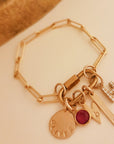 Gold bracelet with various charms on a beige background