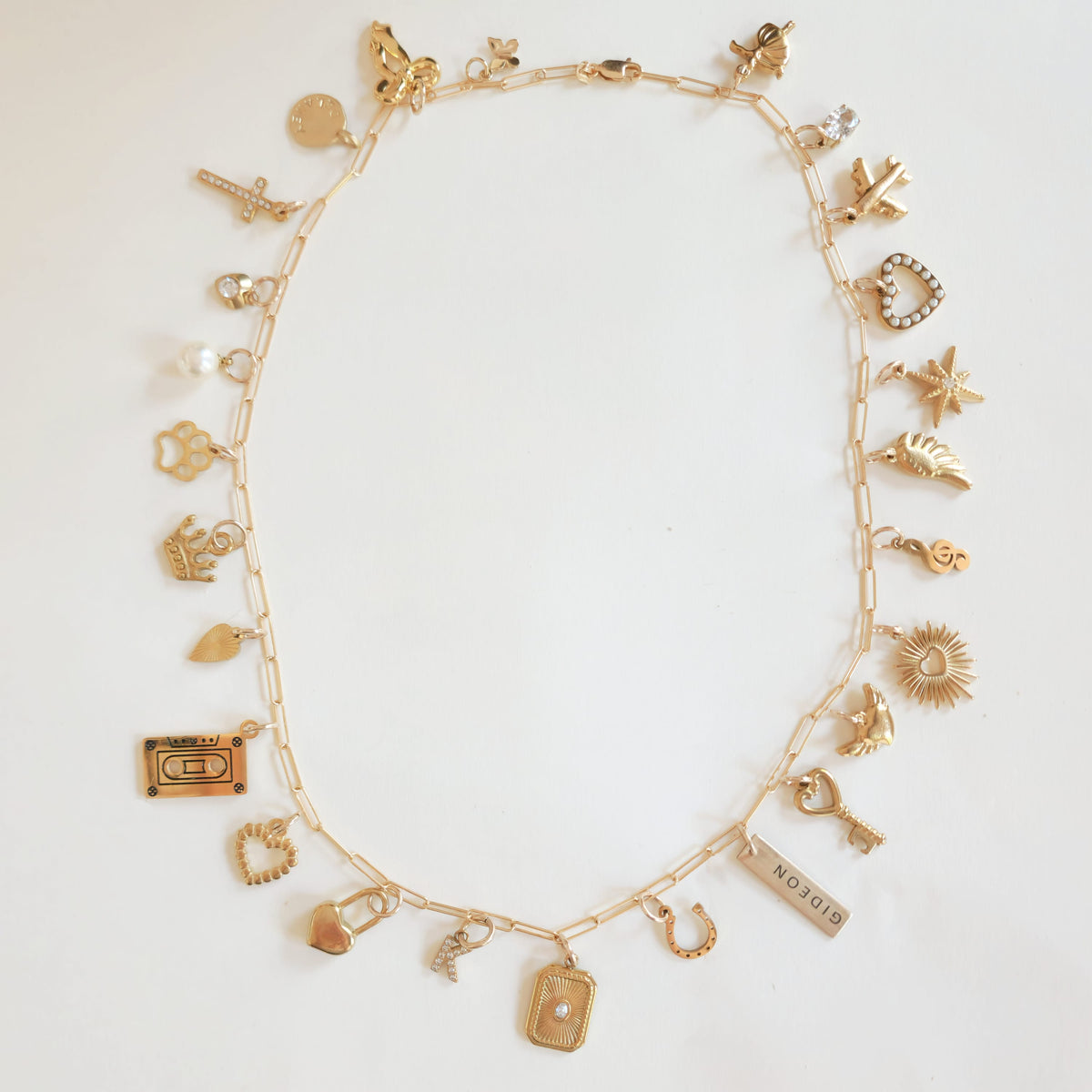 Gold necklace with various charms on a white background