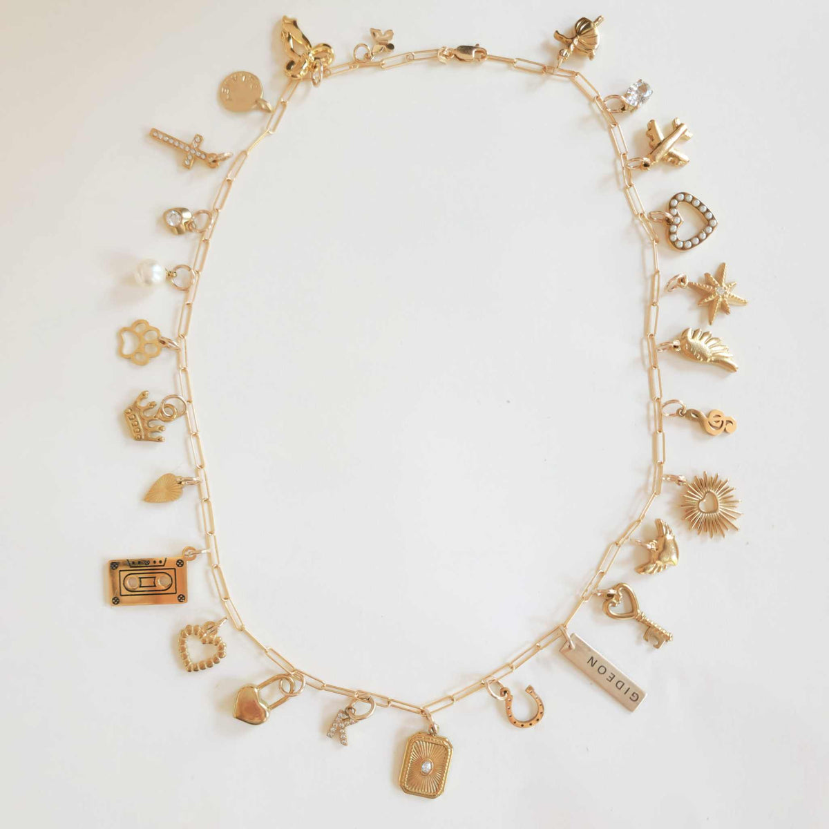 Gold necklace with various charms on a white background