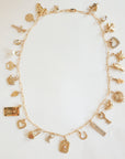 Gold necklace with various charms on a white background