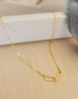 A 14k gold filled cable chain necklace with two larger oval links displayed on a white surface, alongside a grey cloth.