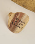Gold pendant with engraved names on a beige background