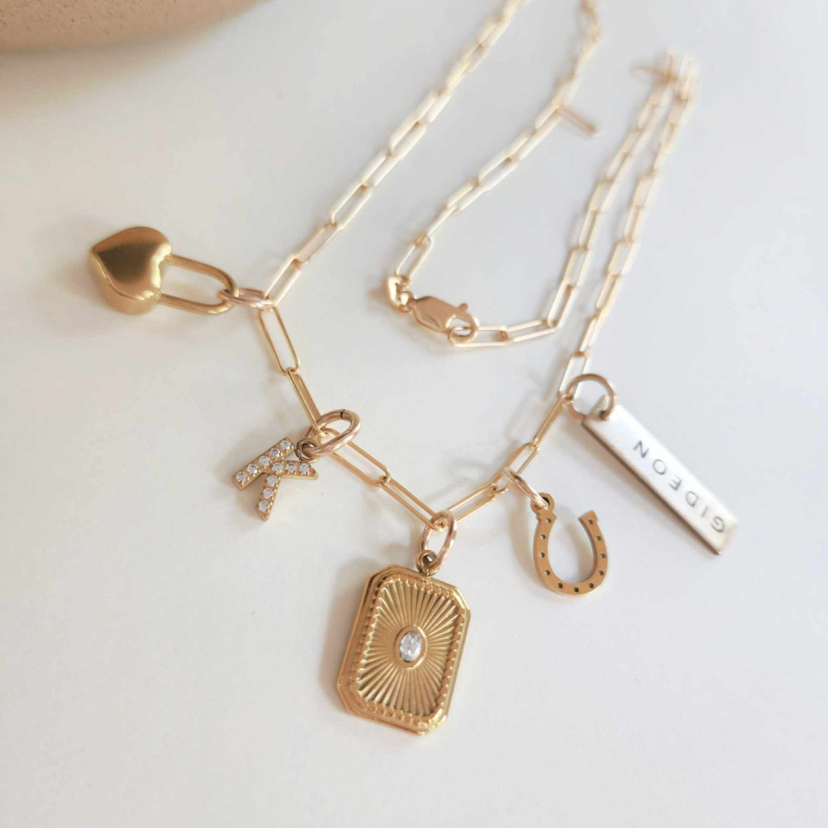 Gold necklace with various charms on a light background
