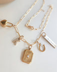 Gold necklace with various charms on a light background