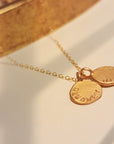 Gold necklace with two round pendants on a light background