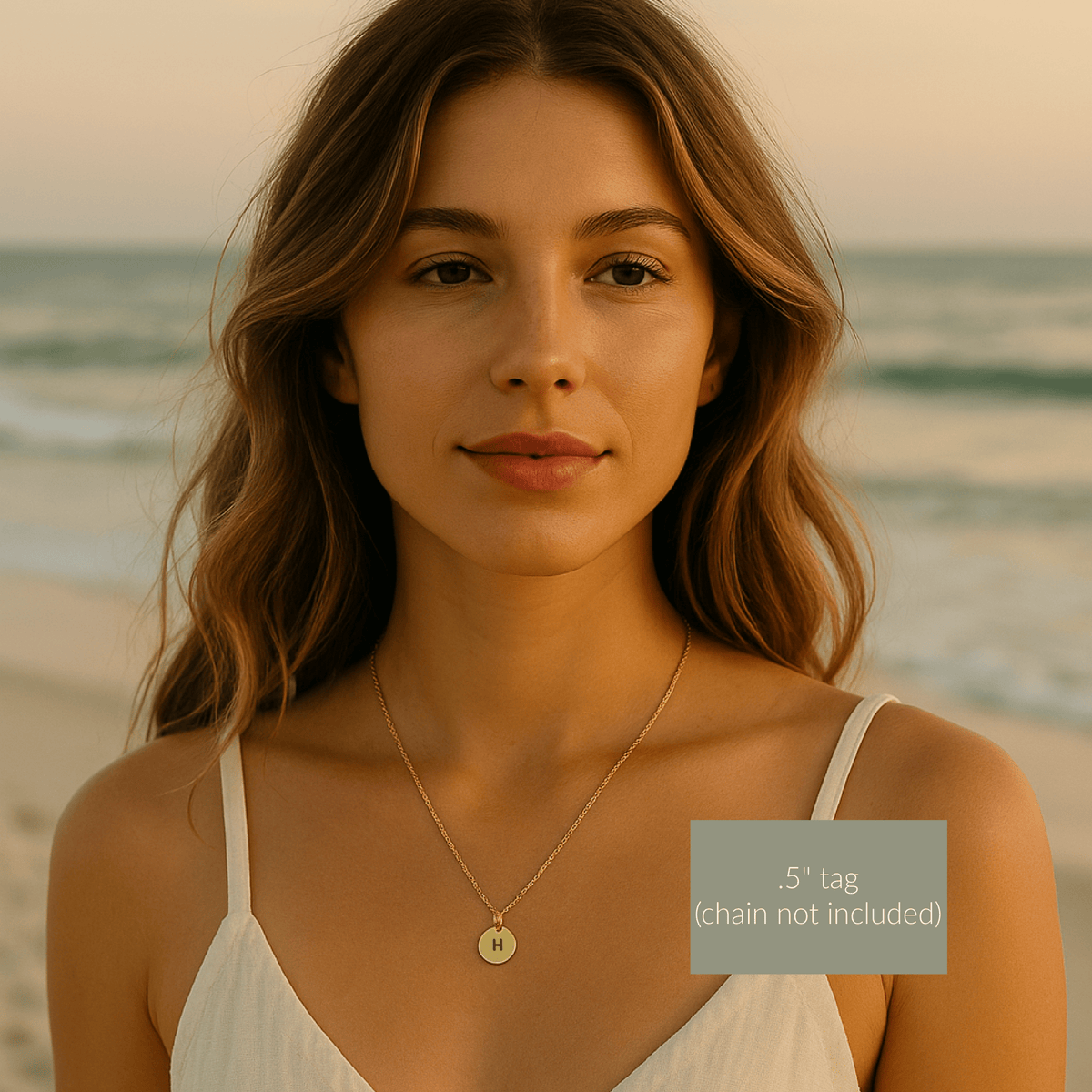 Woman wearing a gold necklace with a 'H' pendant on a beach