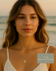 Woman wearing a gold necklace with a 'H' pendant on a beach