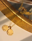 Gold bracelet with engraved charms on a reflective surface