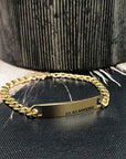 Gold chain bracelet with engraved text on a black textured surface