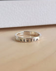 A silver stacking ring with the name 'stella' engraved on it, displayed against a white background.