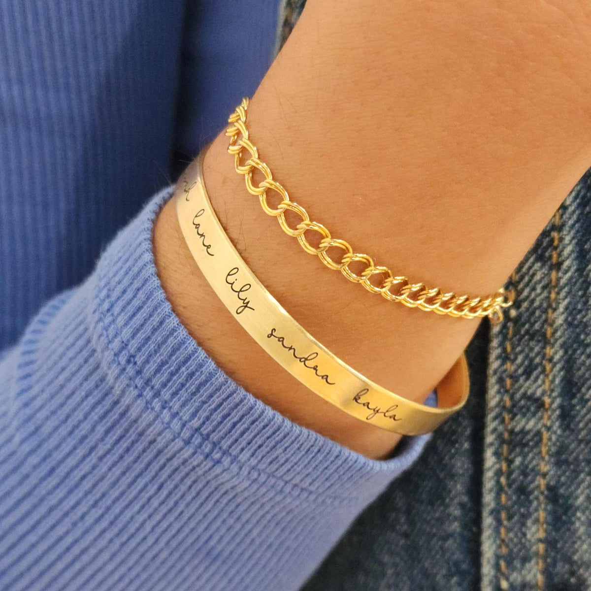 A gold-colored cuff bracelet with custom names engraved