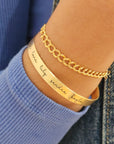 A gold-colored cuff bracelet with custom names engraved
