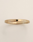 Gold ring with a heart symbol on a beige background