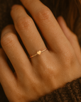 Gold ring with a heart-shaped center on a person's finger against a brown background