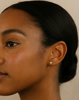 Close-up of a woman's ear with a heart-shaped earring against a neutral background