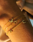 Gold bracelets with letter charms on a wrist
