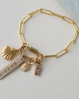 Gold bracelet with charms on a light gray background