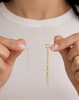 Close-up of hands holding gold and silver chain extensions against a white background