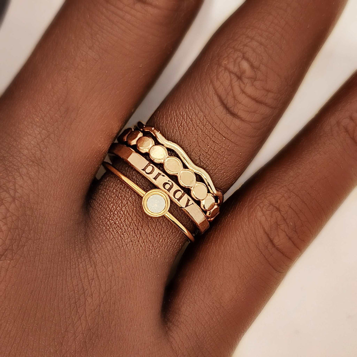 The Harlow Stacking Ring Set featuring four custom 14K gold-filled stackable rings including name engraving, wavy design, beaded texture, and birthstone cubic zirconia