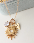 Gold necklace with heart-shaped pendant and clear stone on a light background