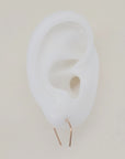Gold U-shaped earrings shown on white silicone ear display