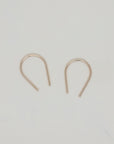 Gold U-shaped minimalist earrings displayed on white surface