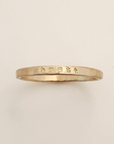 Gold ring with engraved text on a beige background