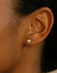Close-up of an ear wearing a gold heart-shaped earring.