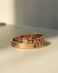 Gold ring with engraved text on a neutral background