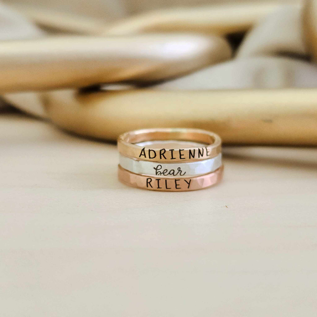 Three handcrafted Elena stacking rings in yellow gold, silver, and rose gold, personalized with custom engravings.