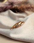 a set of three gold filled rings, including two name rings and one birthstone ring, displayed on a white cloth
