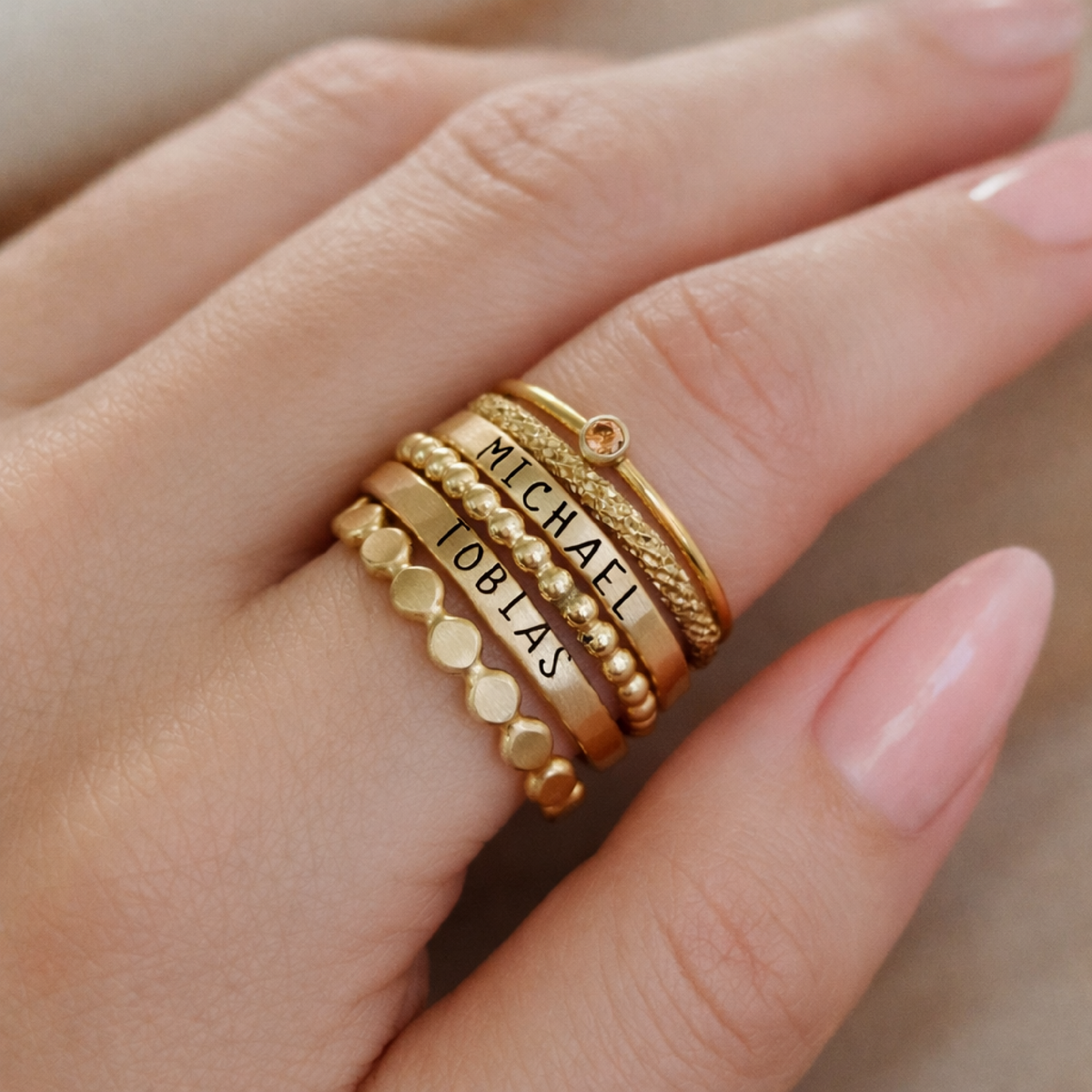 The Ivy stacking name ring set featuring six handcrafted silver and gold rings with birthstone, custom engraving, and beaded designs in a gift box
