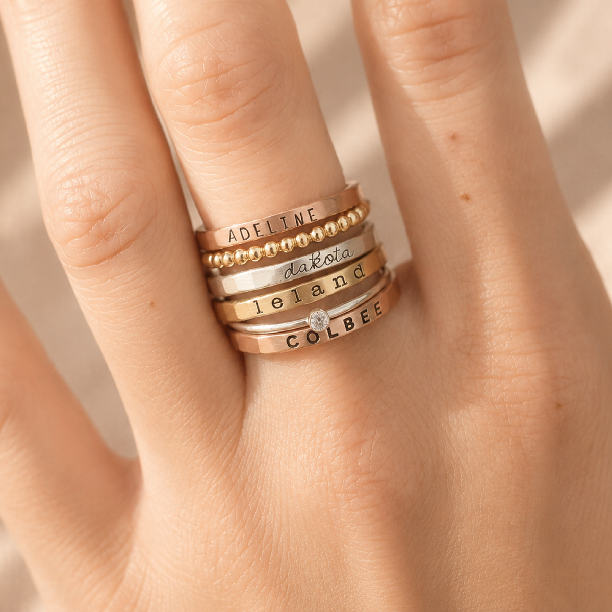 Six-piece custom name ring set with rose gold, yellow gold, fine silver rings, and birthstone, stacked for personalized elegance