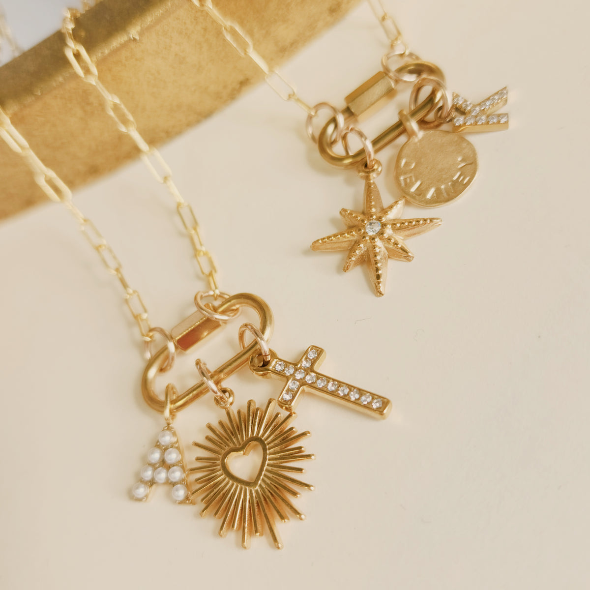 Gold necklace with various charms on a beige background