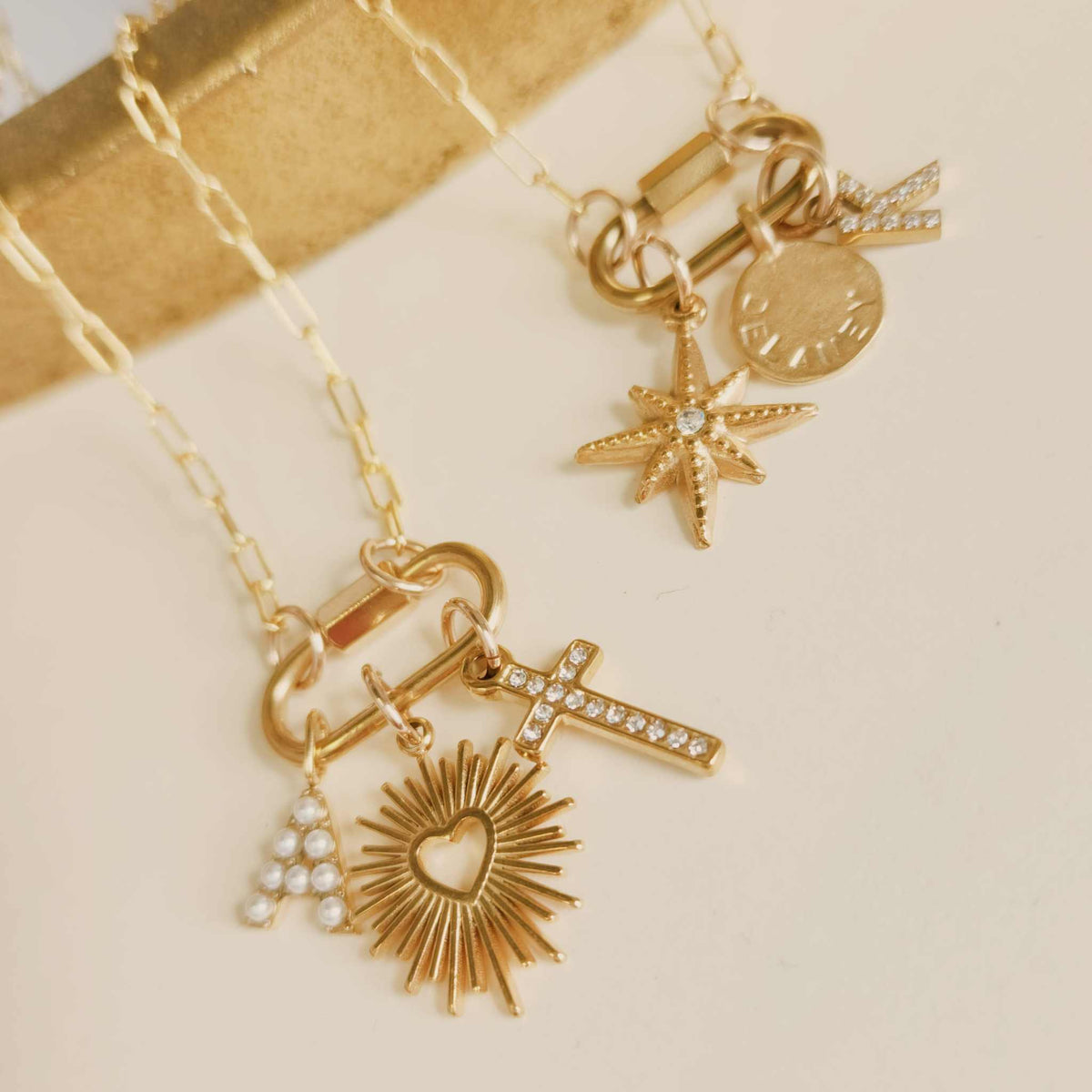 Gold necklace with various charms on a beige background