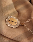 Gold necklace with a round pendant on a beige fabric background